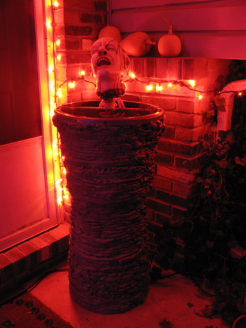 Finally finished the severed head fountain I began a few years back.  Originally, it was the head sitting on the screen over a big black bucket, which pumps water out the ears, nose, and holes in the side of the head.  This year, I glued the bucket on two up-turned plastic buckets, then covered it in layers of Great Stuff foam, which I sprinkled liberally with sand while it was still wet.  Then when it had cured, I spray painted it gray.  It's got a nice gritty texture like stone or cement, and it raises the bleeding head up much closer to eye level.